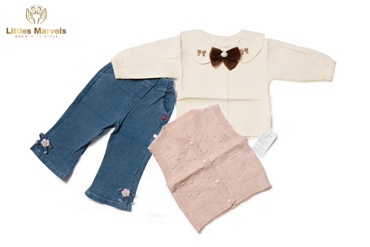 The outfit consists of a cream-colored top with a brown bow and a pair of blue jeans with pink flowers on the bottom